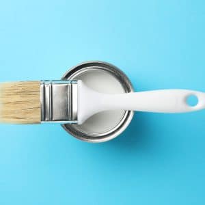 Paint can and brush on blue background, top view