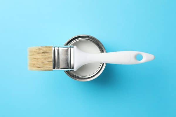 Paint can and brush on blue background, top view