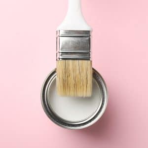 Paint can and brush on pink background, top view