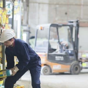 Warehouseman in storehouse lifting sack
