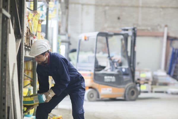 Warehouseman in storehouse lifting sack